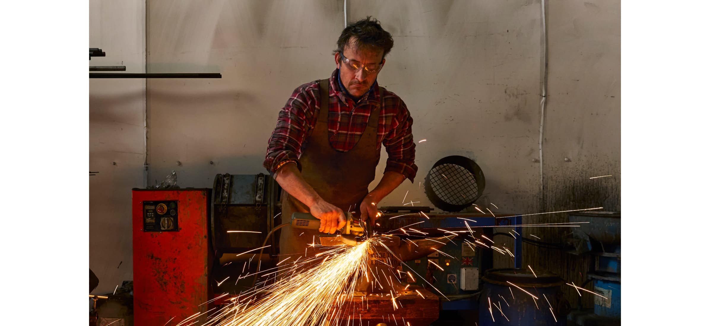 Richard wearing protective glasses as sparks fly at their workbench.
